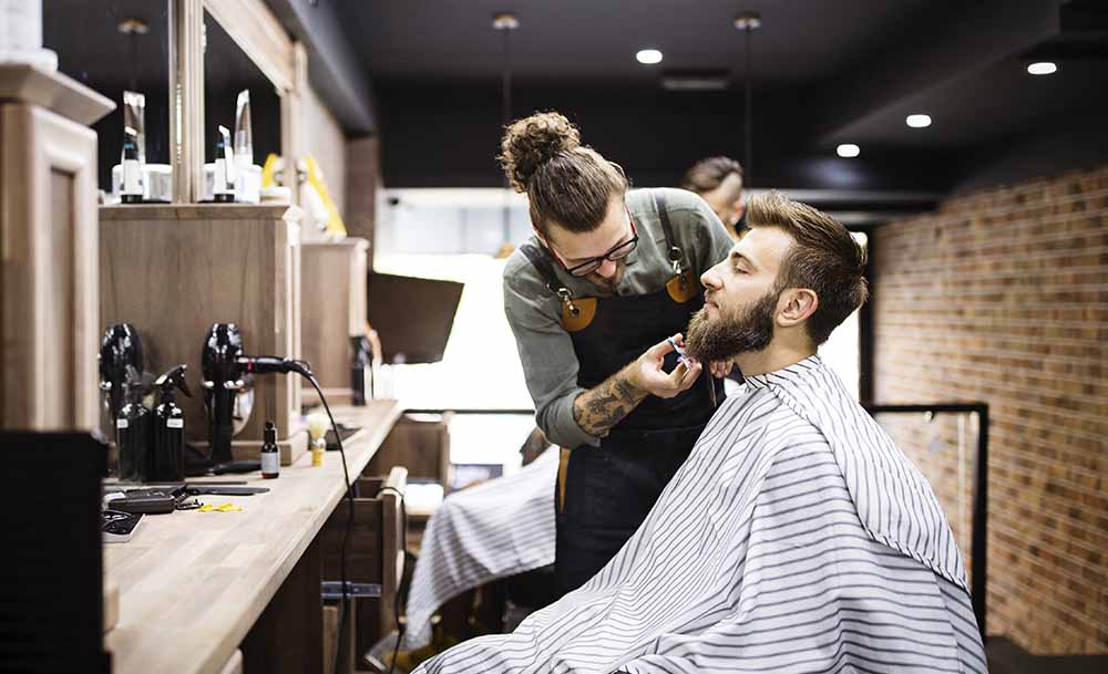 Barber shaving a customer on his business