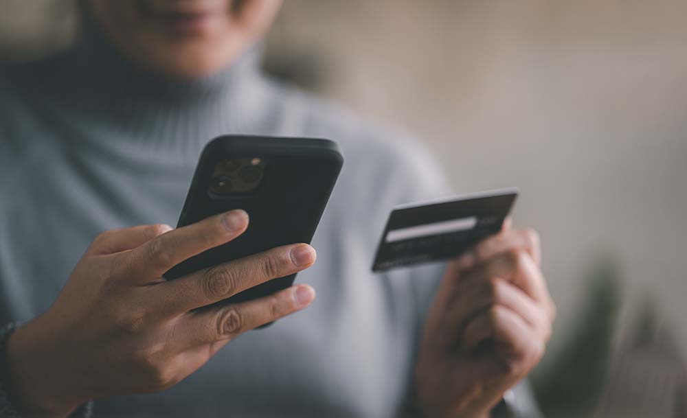 Woman introducing her bank card information into a mobile device