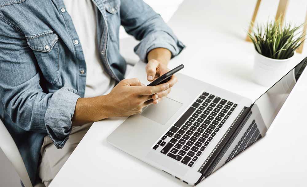 Two people working on tw computers side to side