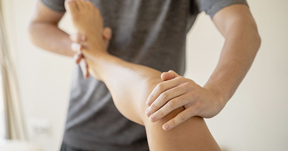 Physiotherapist flexing a patient's leg