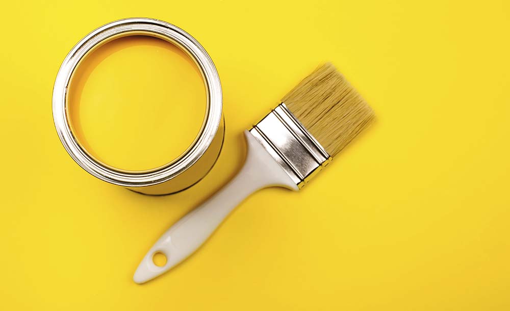 Yellow tub of paint and brush